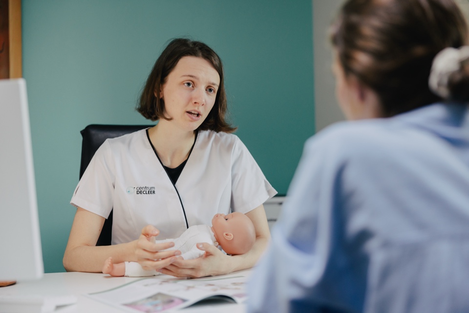 Verloskundige geeft infosessie aan aanstaande ouders met een babypop.