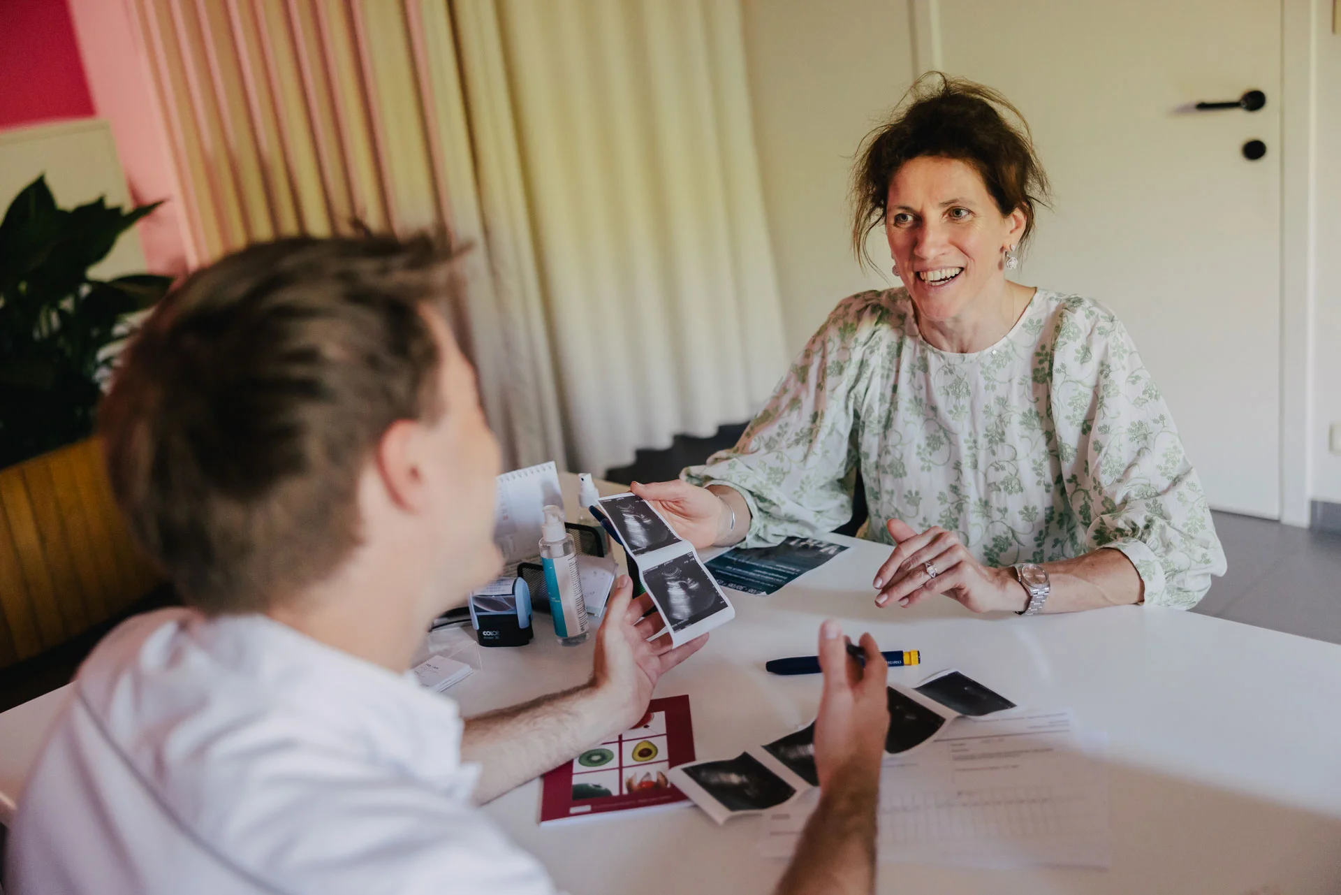 Vrouw bekijkt echo's met man aan tafel, "Over ons