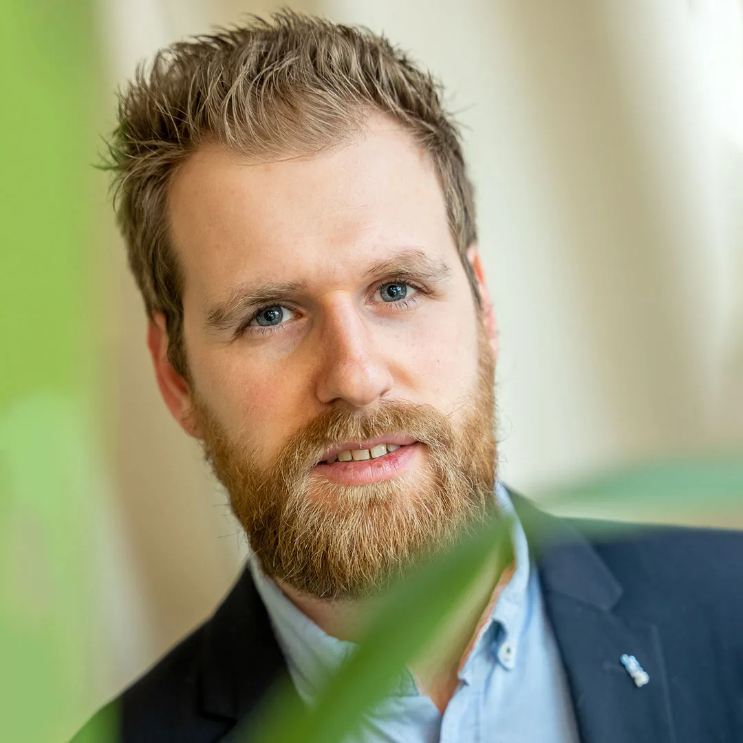 Simon Fransoo, een man met een baard, draagt een blauw overhemd en jasje.