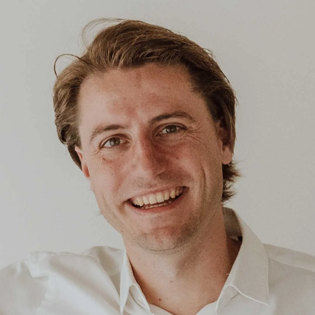 Dr. Jonas Balduyck lachend, portretfoto in wit overhemd.