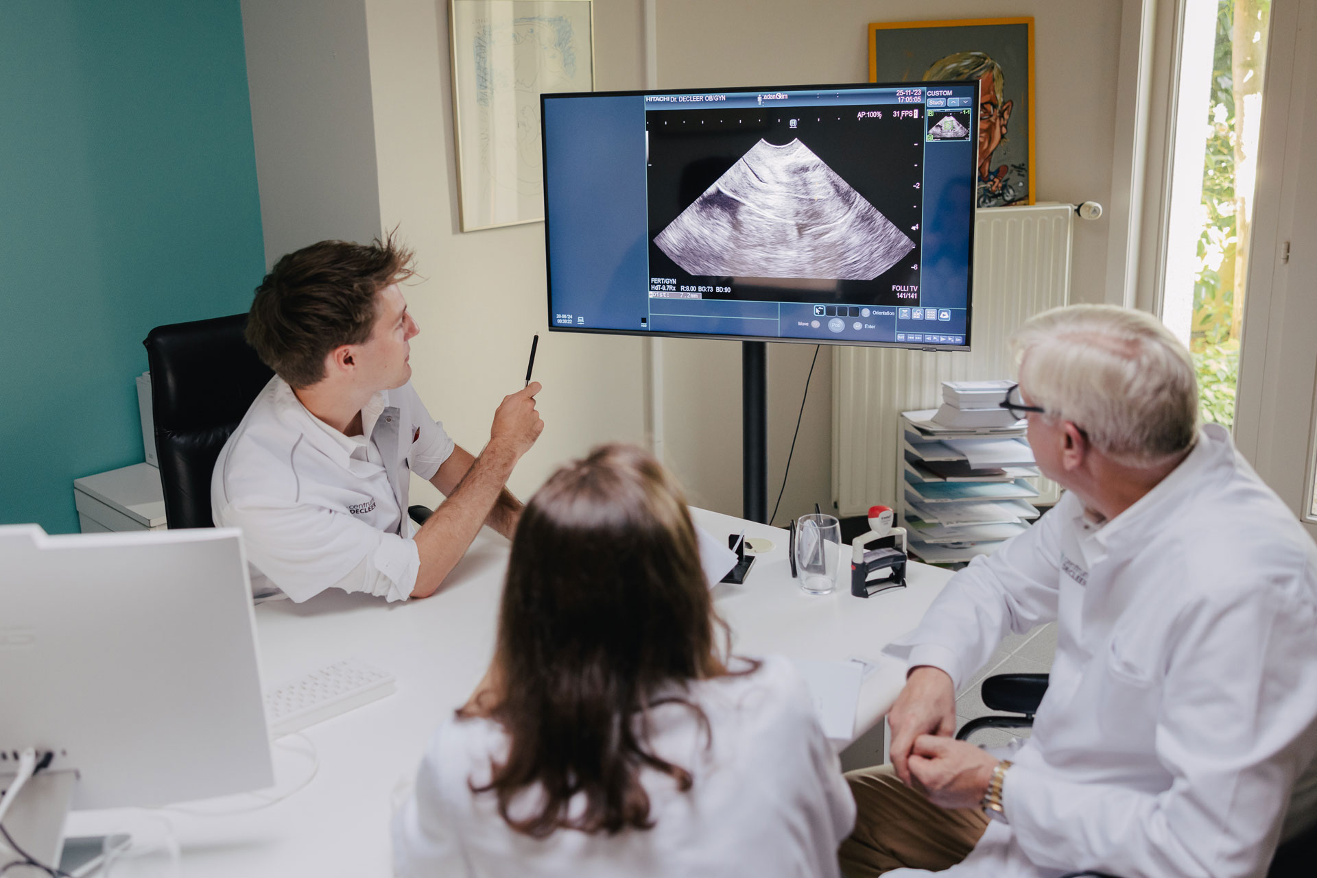 Artsen bespreken een TESE/TESA echo op een scherm. Echografie toont FOLLI TV met 141/141.